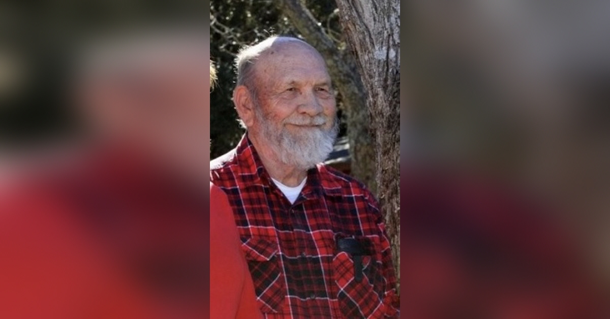 an Elderly John Eddie Vogt in a Red Plaid Shirt Standing Outdoors with a Gentle Smile, Embodying Wisdom and Nostalgia.