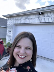 Renita Reavis smiling in front of a home, representing her passion for Texas whiskey and distilling.