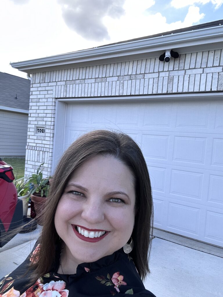 Renita Reavis Smiling in Front of a Home, Representing Her Passion for Texas Whiskey and Distilling.