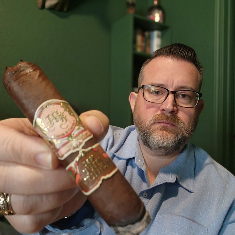Clay Smoot – Cigar Reviewer for the Kendall Gentleman & the Cigar Society - the Kendall Gentleman Clay Smoot, Cigar Reviewer for the Kendall Gentleman and Owner of the Cigar Society, Holds Up a My Father the Judge Cigar, Showcasing Its Bold Design and Rich Wrapper.