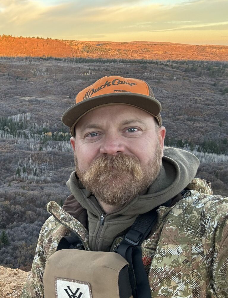 Jed Mazour – Outdoor Contributor for the Kendall Gentleman - the Kendall Gentleman Jed Mazour, Outdoorsman and Contributor to the Kendall Gentleman, Dressed in Camouflage Gear with a Scenic Autumn Mountain Backdrop.