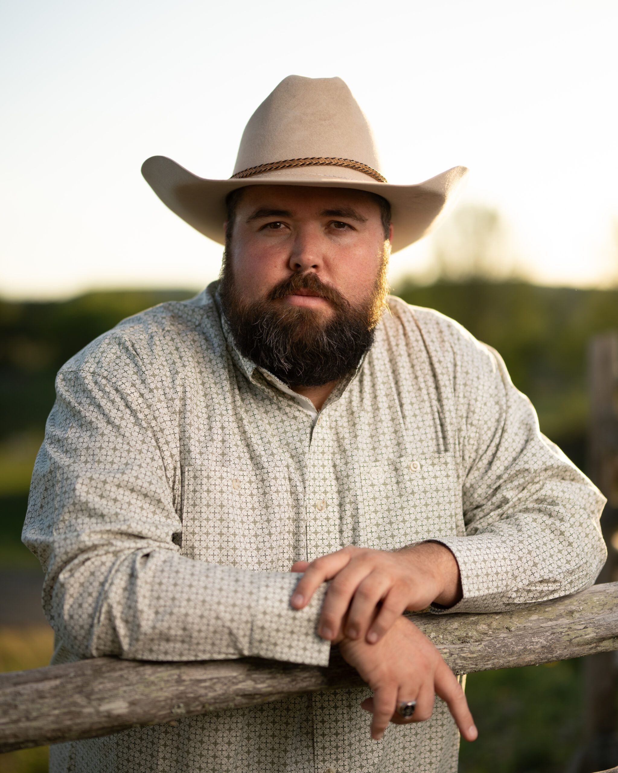 Michael G. Ethridge Stands at a Wooden Fence in the Texas Hill Country, Wearing a Cowboy Hat and a Thoughtful Expression.