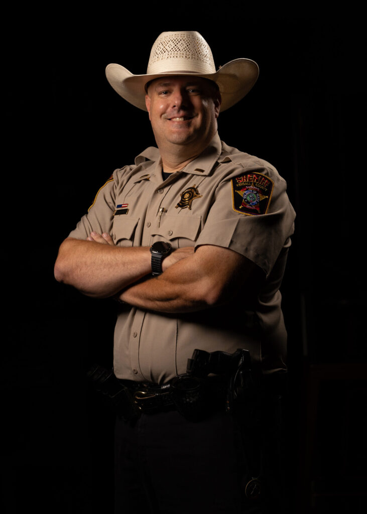 Lieutenant Kevin Klaerner of the Kendall County Sheriff’s Office Stands in Uniform with Arms Crossed and a Confident Smile, Wearing a Cowboy Hat.