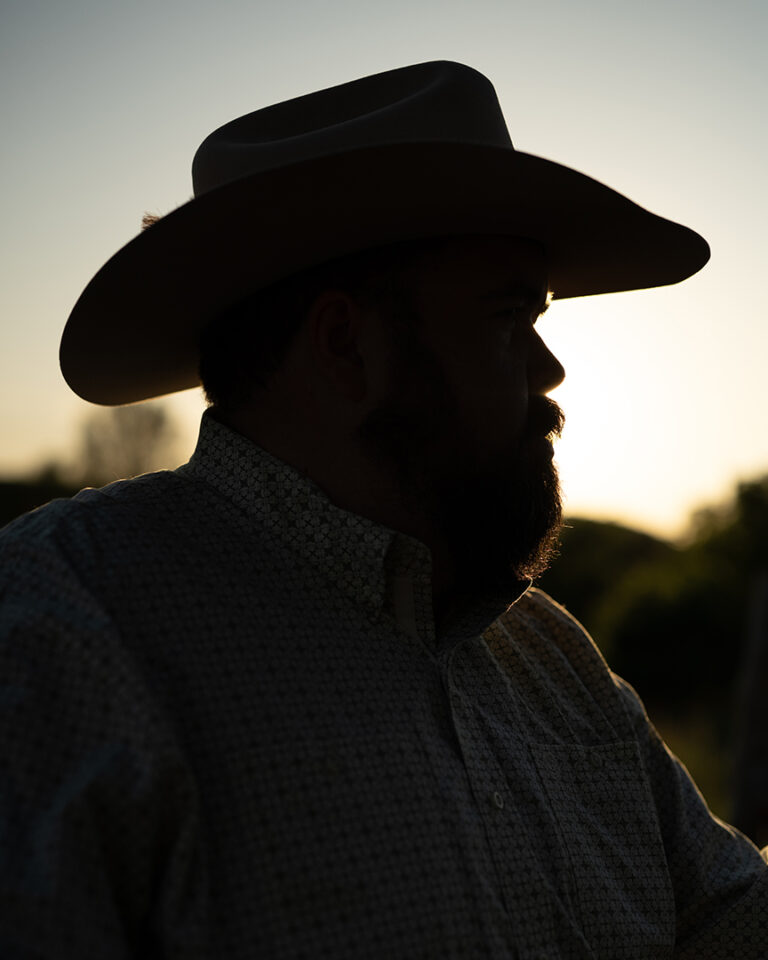 Silhouette of a cowboy in a wide-brimmed hat at sunset, symbolizing stillness and reflection.