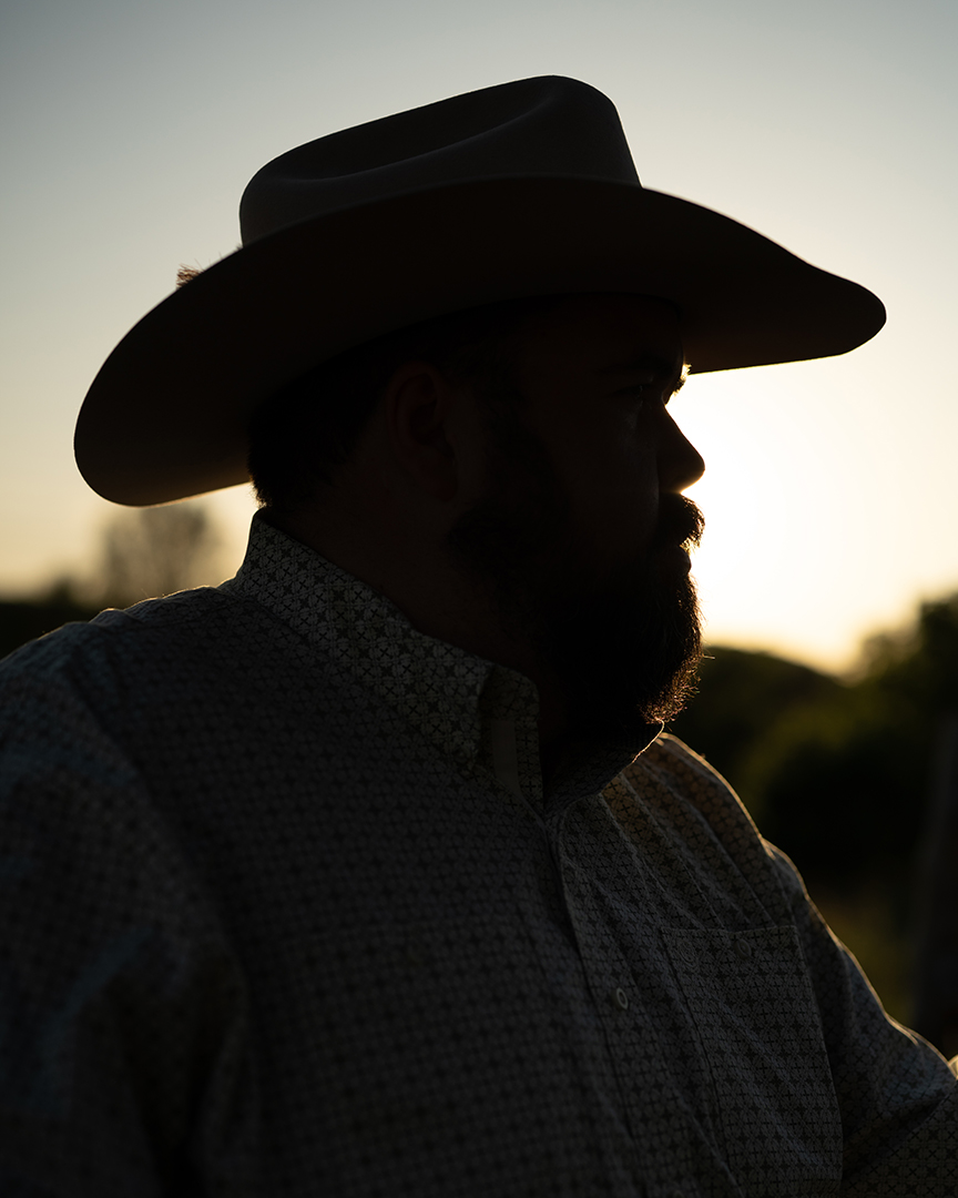 Silhouette of a Cowboy in a Wide-brimmed Hat at Sunset, Symbolizing Stillness and Reflection.