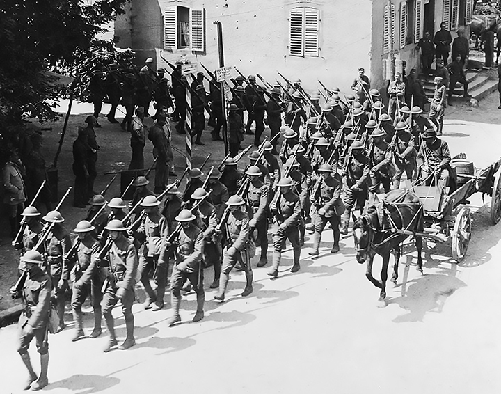 Historic World War I Photograph of U.s. Soldiers Marching in Formation Through a European Village, Rifles Shouldered and Flag Raised.
