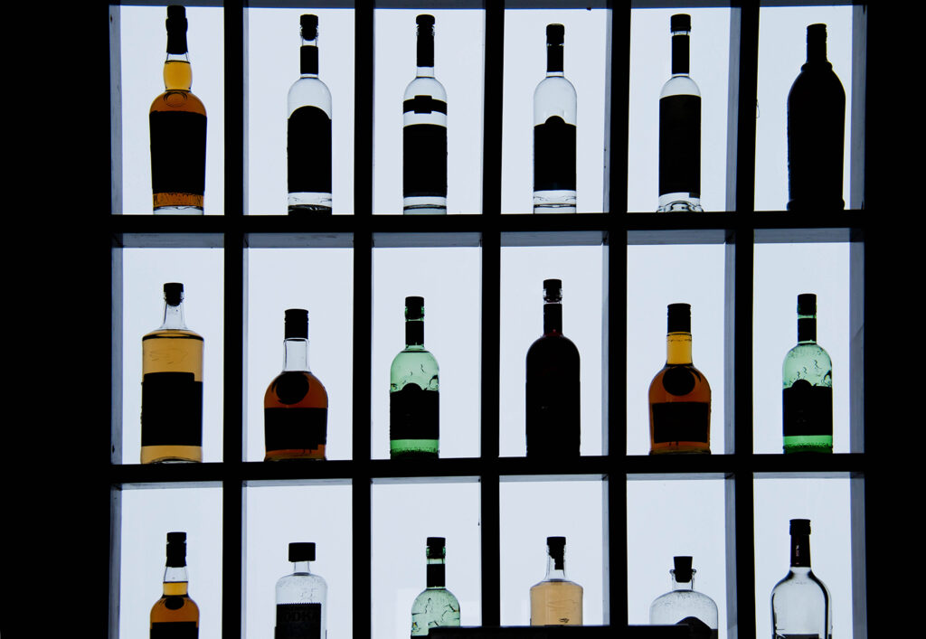 Assorted Bottles on Shelves Minimalist Photography for Modern Design and Advertising - the Kendall Gentleman Assorted Liquor Bottles Displayed in a Backlit Grid Shelf, Creating Silhouettes Against a Bright Background.