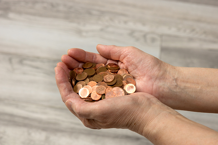 Hands holding a collection of pennies, symbolizing thrift and careful saving in early Boerne, Texas.