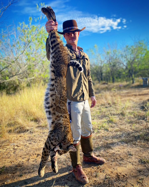 Hunter holding a harvested bobcat on a South Texas ranch near Pearsall, Texas.