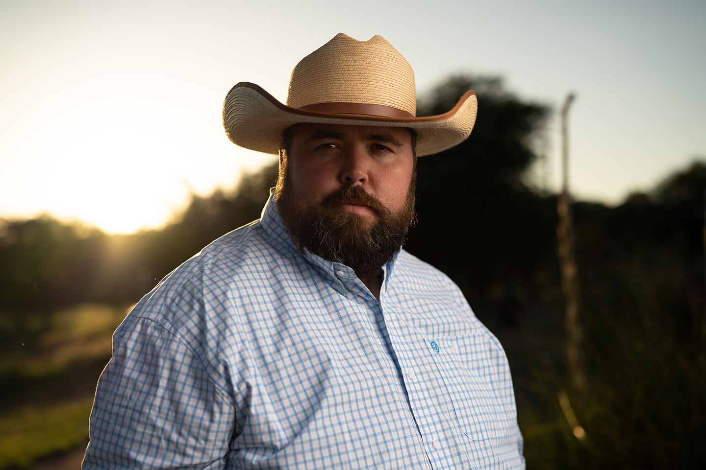 Portrait of the Kendall Gentleman Publisher Standing Outdoors in the Texas Hill Country at Sunset Wearing a Cowboy Hat