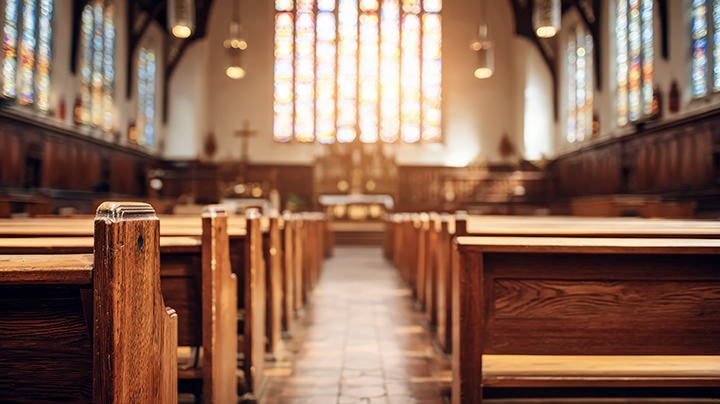 Interior of a Church Sanctuary with Wooden Pews Leading Toward a Stained Glass Altar.