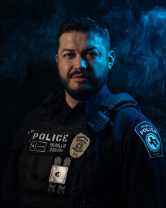 Portrait of Boerne Police Officer Eduardo Murillo in tactical uniform, illuminated by dramatic blue lighting and smoke, featured in the Hope for Heroes article by Jonathan Mallard for The Kendall Gentleman.