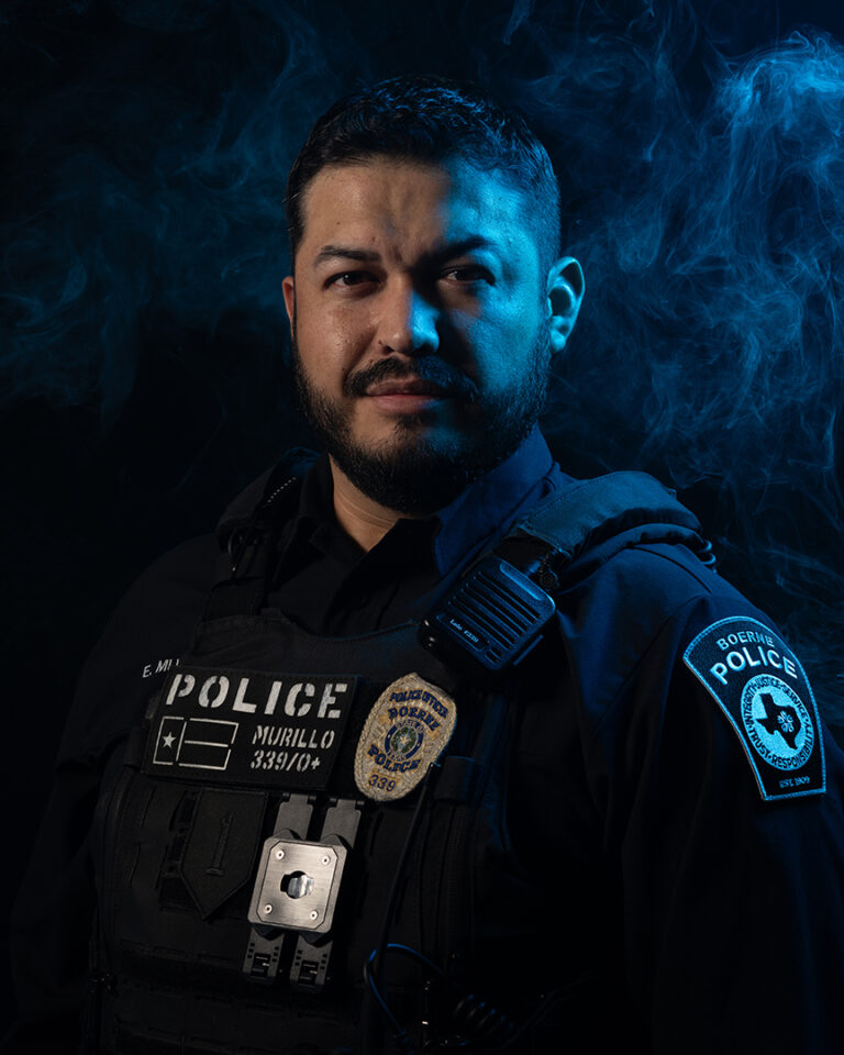 Portrait of Boerne Police Officer Eduardo Murillo in Tactical Uniform, Illuminated by Dramatic Blue Lighting and Smoke, Featured in the Hope for Heroes Article by Jonathan Mallard for the Kendall Gentleman.