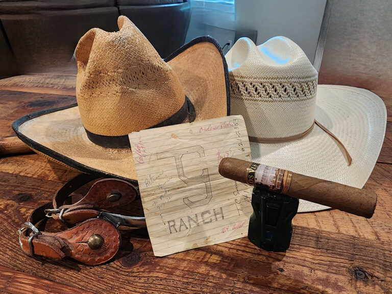 Los Vista Cigars' the '64 Robusto Resting on a Torch Lighter Beside Cowboy Hats and Spurs, Boerne, Texas
