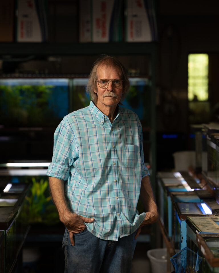 Peyton Turk Standing Among Fish Tanks at Red Crest Pet Shop in Boerne, Texas