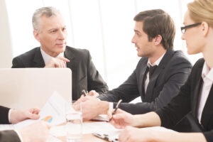 Business People in Formalwear Seated Together at a Meeting Table