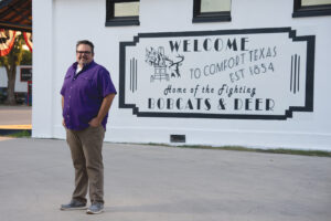 Wes Holekamp Standing in Front of the Welcome to Comfort Texas Mural