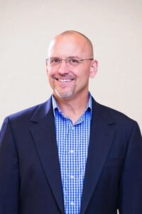 Paul Stephenson in Glasses, a Navy Blazer and a Blue Checked Shirt