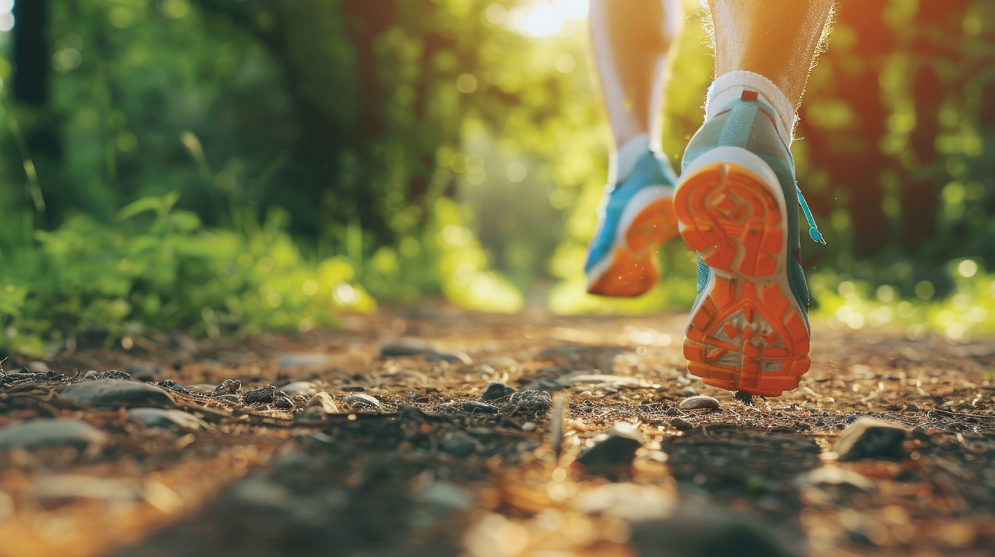 Runner's Legs and Blue Running Shoes on a Sunlit Dirt Trail